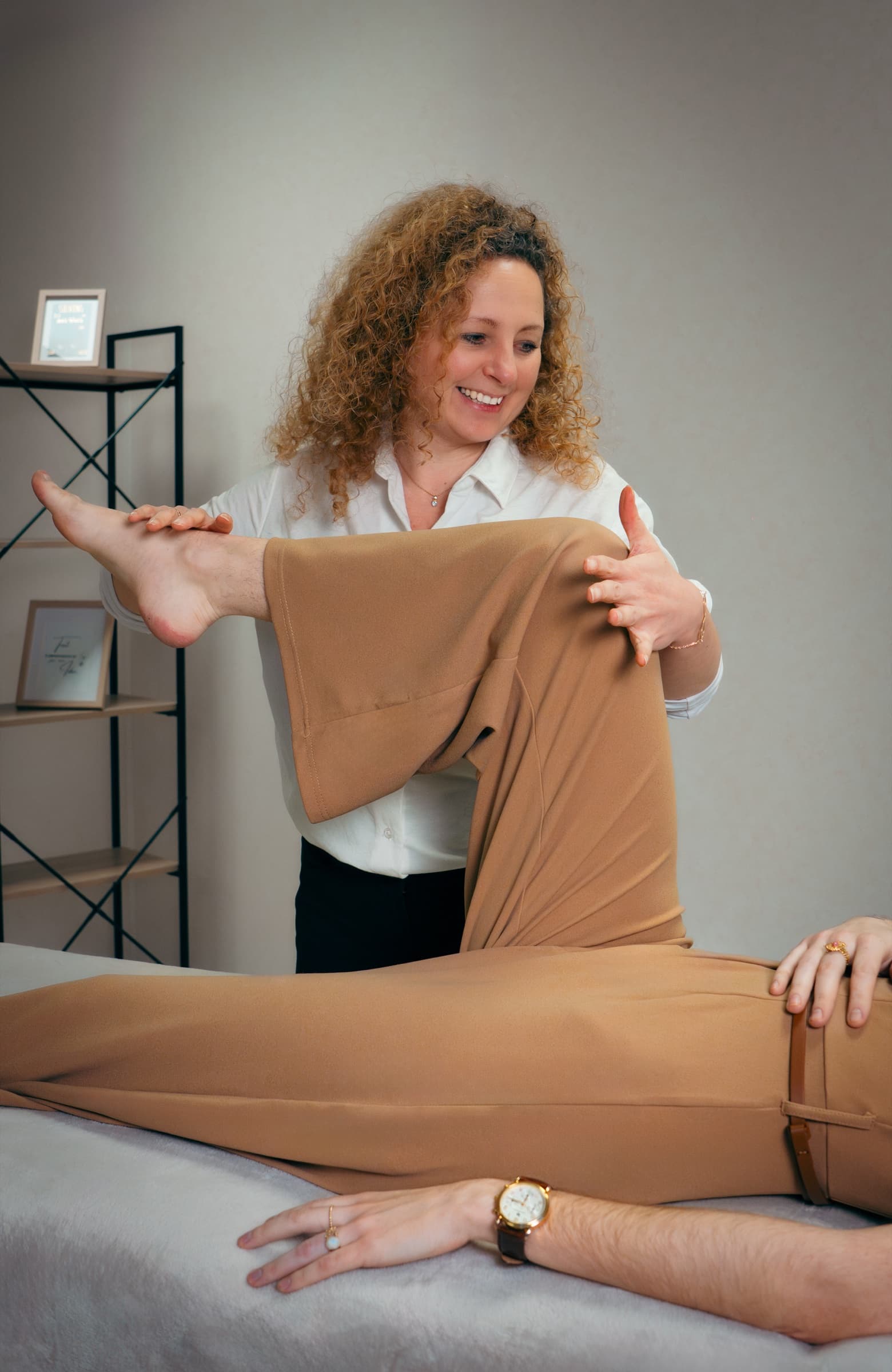 Odile accompagne doucement le mouvement de la jambe pendant une séance